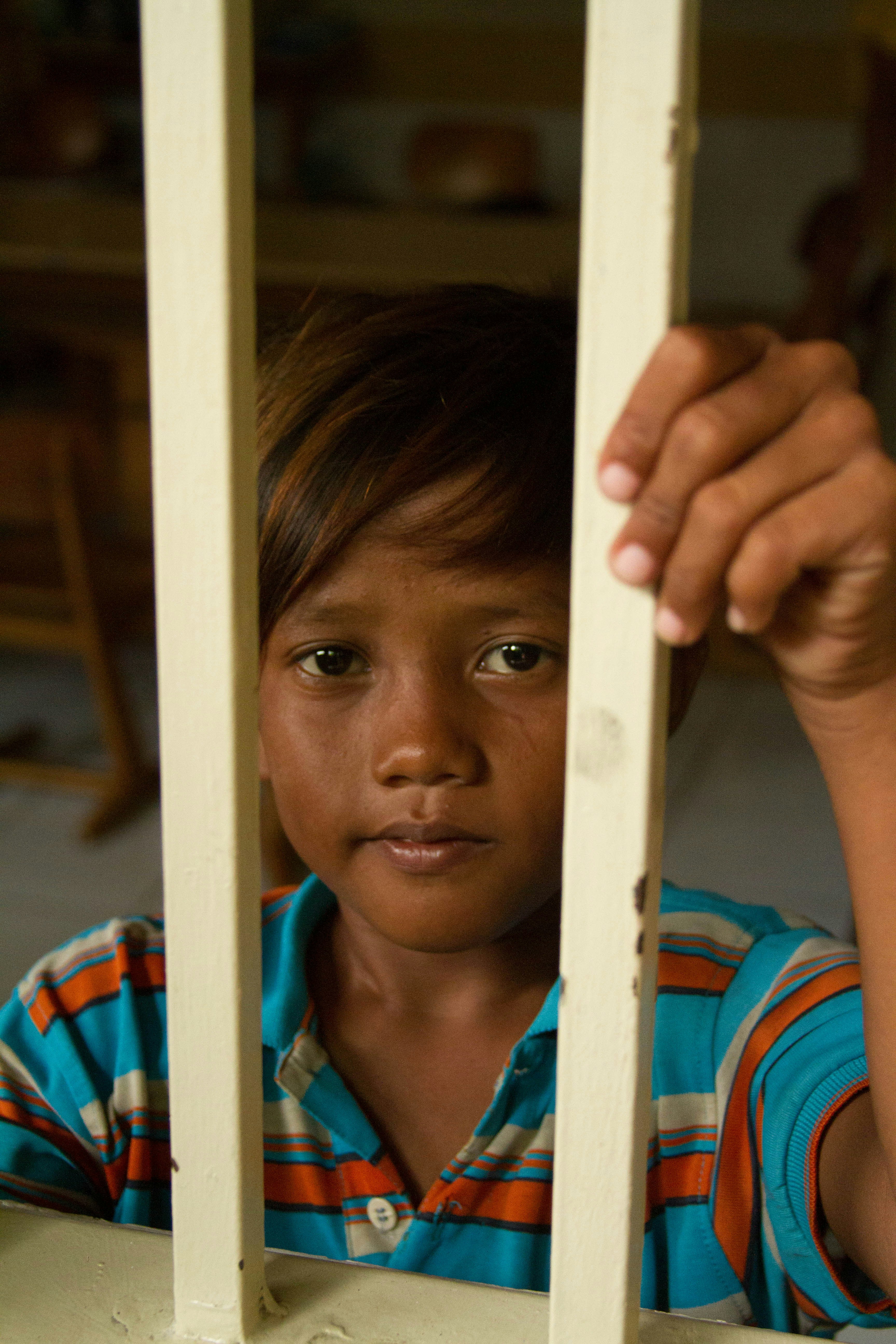 Child looking through white fence